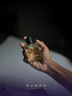 The amber Infinity bottle held in low light, its black cap in shadow